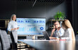 © insta_photos - Middle aged happy successful Asian business woman ceo executive manager presenting to colleagues trainees interns income revenue financial data research results on big screen in modern office.