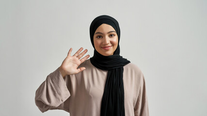 Wall Mural - Happy young arabian woman in hijab waving hand