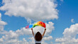 © OksanaFedorchuk - Blonde, lesbian, woman holding a rainbow LGBT gender identity flag on sky background with clouds on a sunny day and celebrating a gay parade, Bisexuality or Coming Out Day
