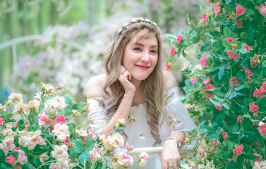 Portrait beautiful woman tourist posing happiness with smile ,she wearing a nice dress to travel in garden colorful flowers blooming for a summer vacation with beautiful flower garden background.