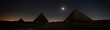 Giza pyramids light up during sound and light show to celebrate Ramadan Feast festival in Cairo, Egypt. The pyramids of Cheops and Chephren and mykerin under the night starry sky and the moon.