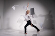 A graceful ballerina in a business suit throws documents in the studio. Business woman dance barefoot on a white background