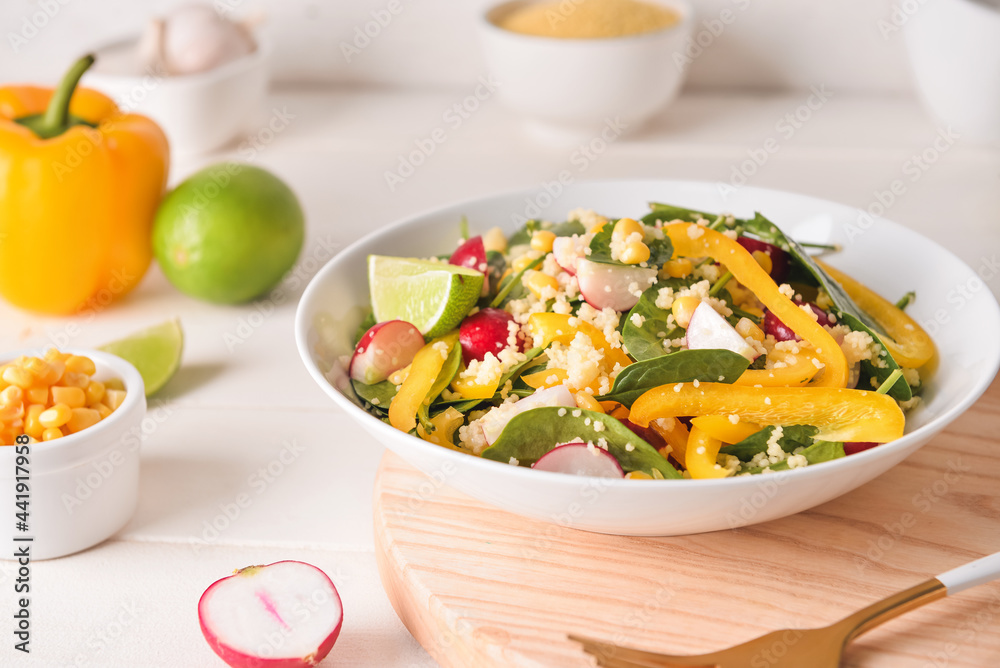 Bowl with couscous and vegetables on light wooden background, closeup