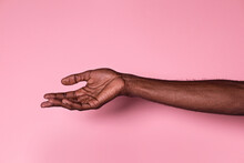 Hand Of Anonymous Black Man With Palm Upwards Against Pink Background