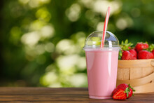 Strawberry Milkshake In Disposable Plastic Glass On Wooden Table