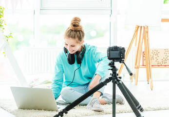 Wall Mural - Smiling girl using laptop and camera