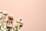 Bottle of luxury perfume and fresh jasmine flowers on beige background, flat lay. Space for text