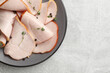 Delicious cut ham with thyme and peppercorns on light grey table, top view. Space for text