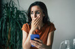 © My Ocean studio - Sad, frustrated young brunette woman is crying with smartphone in hands while she sitting on the chair at apartment