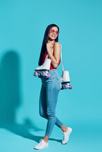 Full Length Of Attractive Young Woman Looking Away And Smiling While Carrying Roller Skates