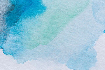 Macro close-up of an abstract blue, light blue and turquoise watercolor gradient fill background with watercolour stains. High resolution full frame textured white paper background.