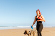 Sportswoman with German Shepherd walking on ocean beach