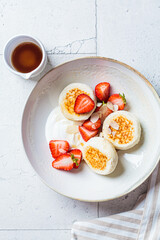 Poster - Homemade cottage cheese fritters syrniki with strawberries and maple syrup, Russian and Ukrainian cuisine concept.