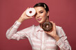 © millaf (Nemchinova) - Young woman holding chocolate and sugar donuts on red background portrait