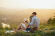 © eduard - A loving couple is enjoying a summer picnic, beautiful landscape and sunset with wine.