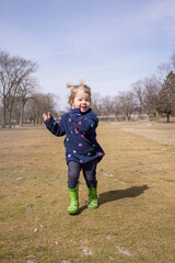 Wall Mural - 2 year old toddler running in the grass in the spring