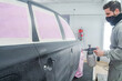 © ADDICTIVE STOCK - Man with spray gun painting car in workshop