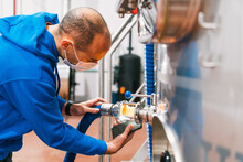 Engineer With Smartphone Examining Filter Tube In Brewery