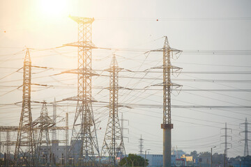 A distribution substation with power lines and transformers. Energy and industry. Industrial High Voltage Converter metal structure and power lines, photography at sunset. Sub-station