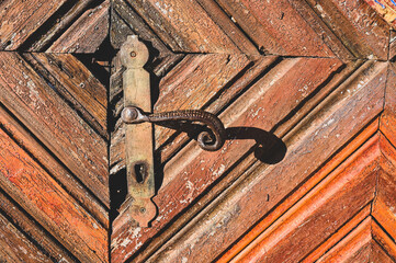 Old Door handle, close up. Ancient rusty door handle on brown old wooden door. House gate.