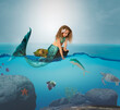 © ShannonK - Curly hair little girl mermaid on floating rock in ocean feeding a fish