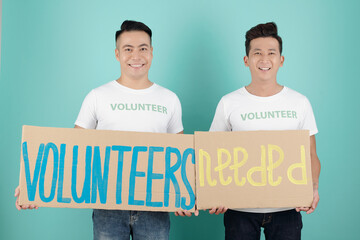 Wall Mural - Smiling young men inviting new volunteers in their charitable foundation, isolated on turquoise