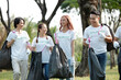 © DragonImages - Group of cheerful friends volunteering in local park and picking up trash to clean the ground