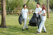 © DragonImages - Young smiling friends joking around when picking up garbage on campus or in city park