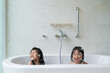© Odua Images - two happy asian girl taking a bath together on a bathtub