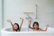© Odua Images - two happy asian girl taking a bath together on a bathtub