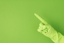Photo Of Hand In Green Rubber Glove Making Pointing Symbol With Forefinger On Isolated Green Background With Copyspace
