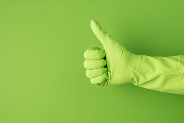 Profile photo of hand in green glove making thumb-up on isolated green background with copyspace