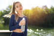 © fotofabrika - Portrait of young beautiful woman wearing blue sportswear drinking water at park