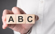 Business man hand holding wooden cube with abc text. Financial, marketing and business concepts
