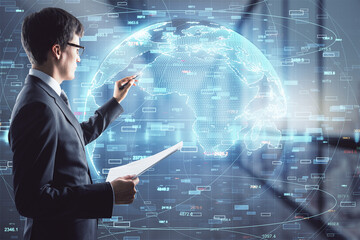 Poster - Attractive young european businessman standing in blurry office interior with glowing globe and tech hologram. Global innovation and big data concept. Double exposure.