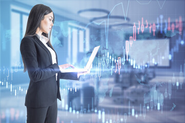 Canvas Print - Pretty young european businesswoman with laptop standing in blurry office interior with forex chart. Trade and stock market concept. Double exposure.