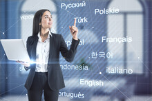 Happy Young European Businesswoman With Laptop Pointing Up In Blurry Office Interior With Creative Languages Mesh. Online Education And Translation Concept. Double Exposure.