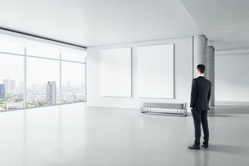Poster - Businessman in modern gallery interior with empty poster on concrete wall and window with city view. Mock up.