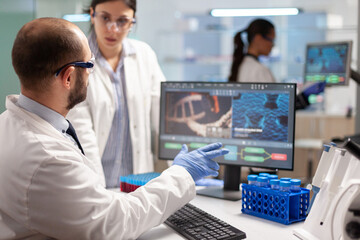 Medical team scientist conducting DNA experiments looking in computer holding test tube with blood sample. Chemists stuff analysing virus evolution using high tech technology for treatment research.