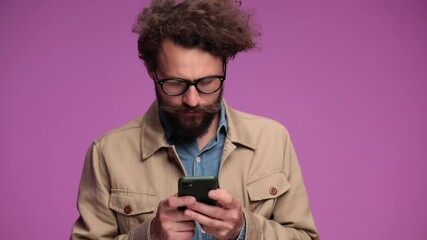 Sticker - handsome young casual man texting and writing emails, looking up, smiling and making thumbs up gesture on pink background