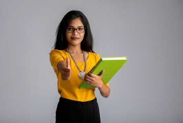 Wall Mural - Pretty young girl posing with the book on grey background