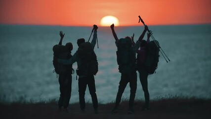 Wall Mural - the four travelers have fun on the sea shore on sunset background. slow motion