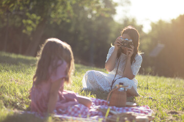 Wall Mural - Mother and daughter sitting in nature. Mother photographs her kid.