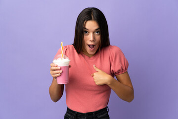 Wall Mural - Teenager girl holding a strawberry milkshake with surprise facial expression