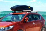 Fototapeta  - Travel to the sea by car. Crossover with roof rack stands against the background of the sea.