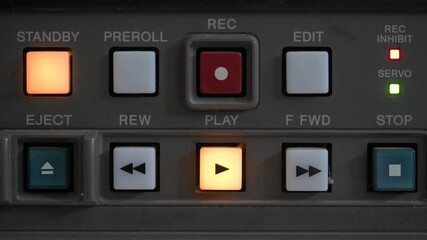 Close up of the control panel of an old broadcasting recorder where we can see the play buttons while a person presses the play and stop button