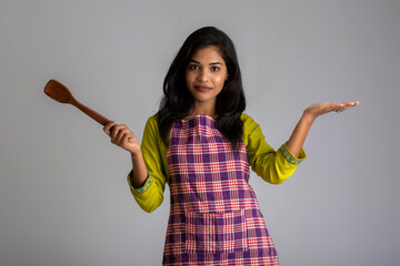 Young girl holding and posing with kitchen utensils spatula on a grey background