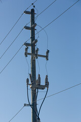 Powerlines and insulators at a pole in front of a blue sky