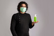 Portrait of young man using or showing a sanitizing gel from a bottle for hands cleaning.