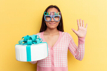 Wall Mural - Young mixed race woman holding a cake isolated on yellow background smiling cheerful showing number five with fingers.